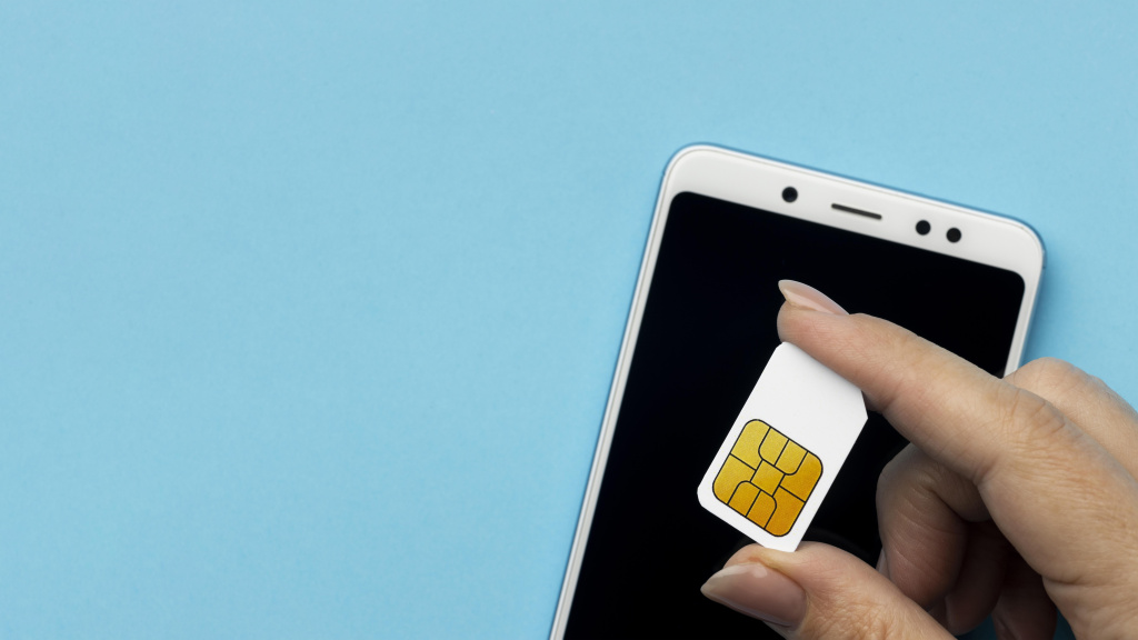 top-view-of-hand-holding-sim-card-with-smartphone-and-copy-space.jpg